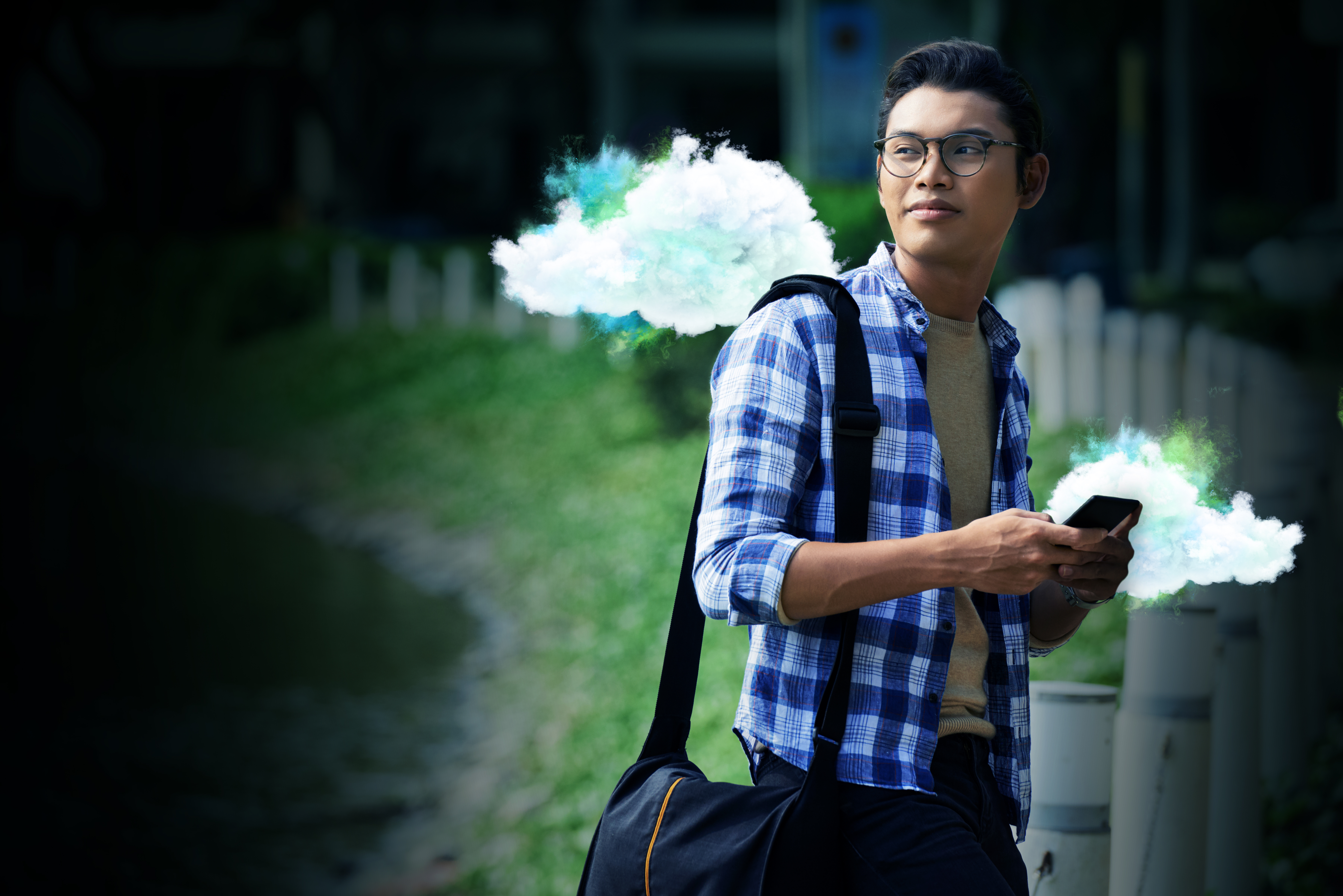 Student looking over their shoulder holding an iPhone whilst smiling